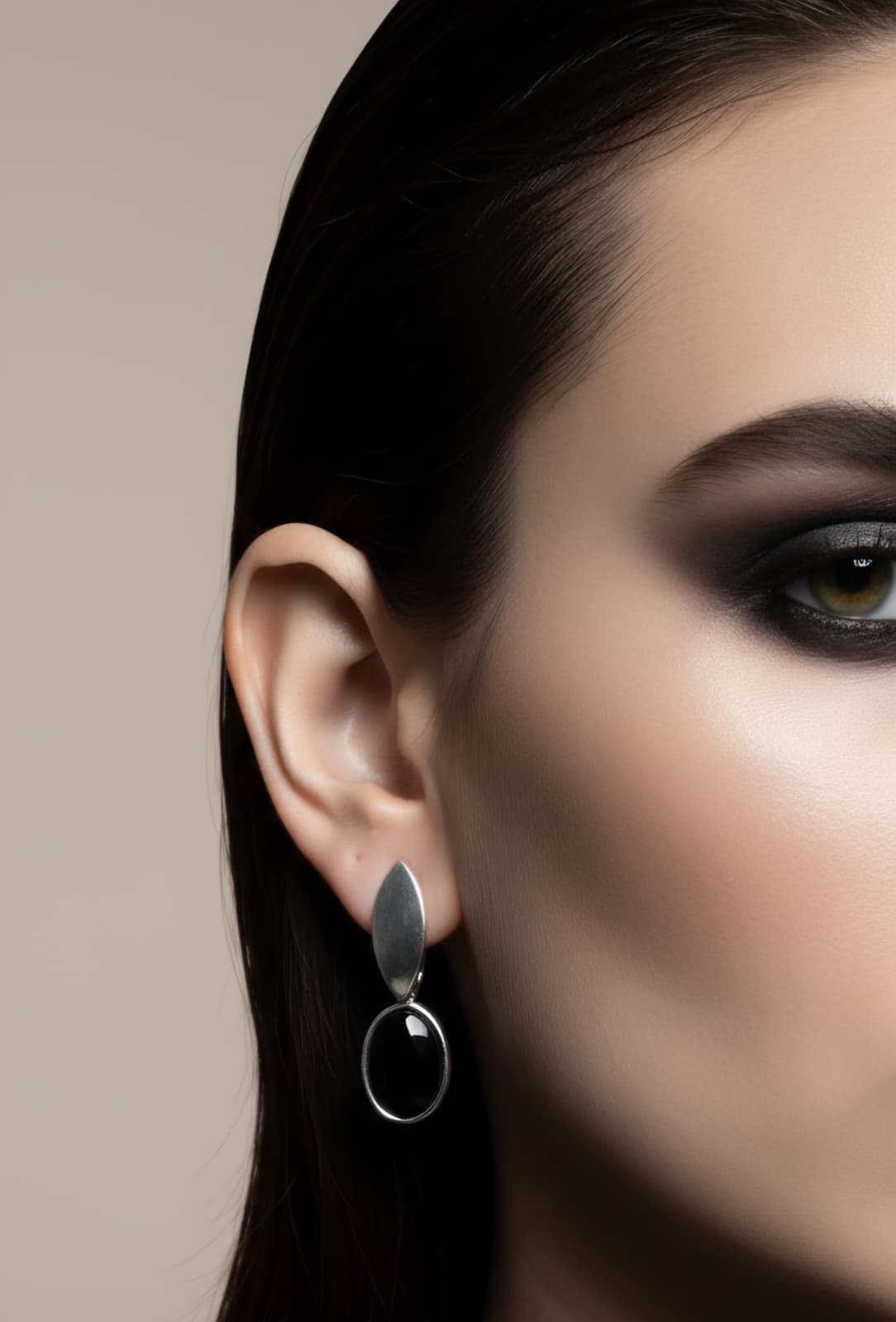 Close-up of a woman's ear wearing a silver earring with a blurred background