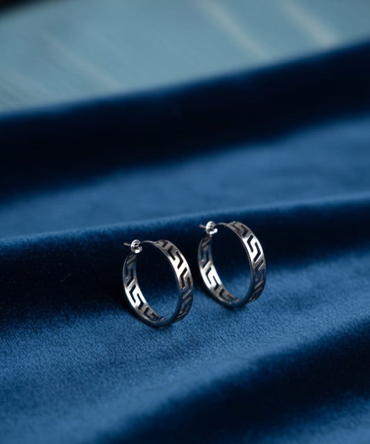 Silver hoop earrings on a blue fabric background