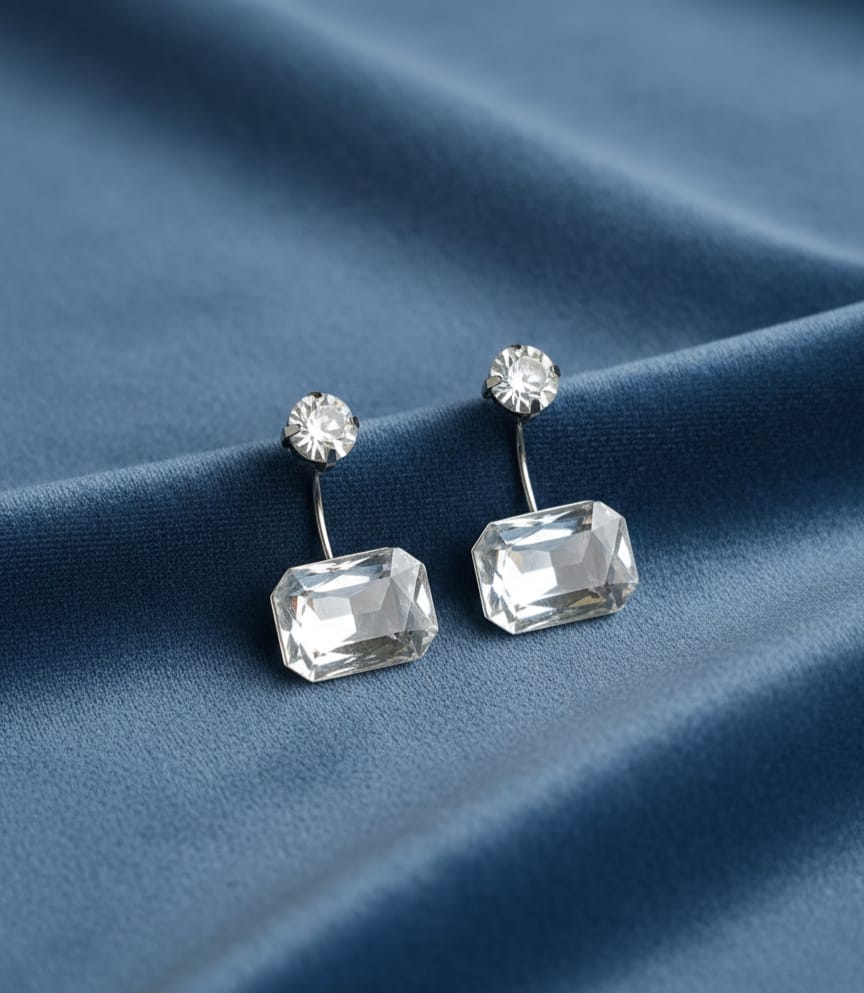Pair of crystal earrings on a blue fabric background