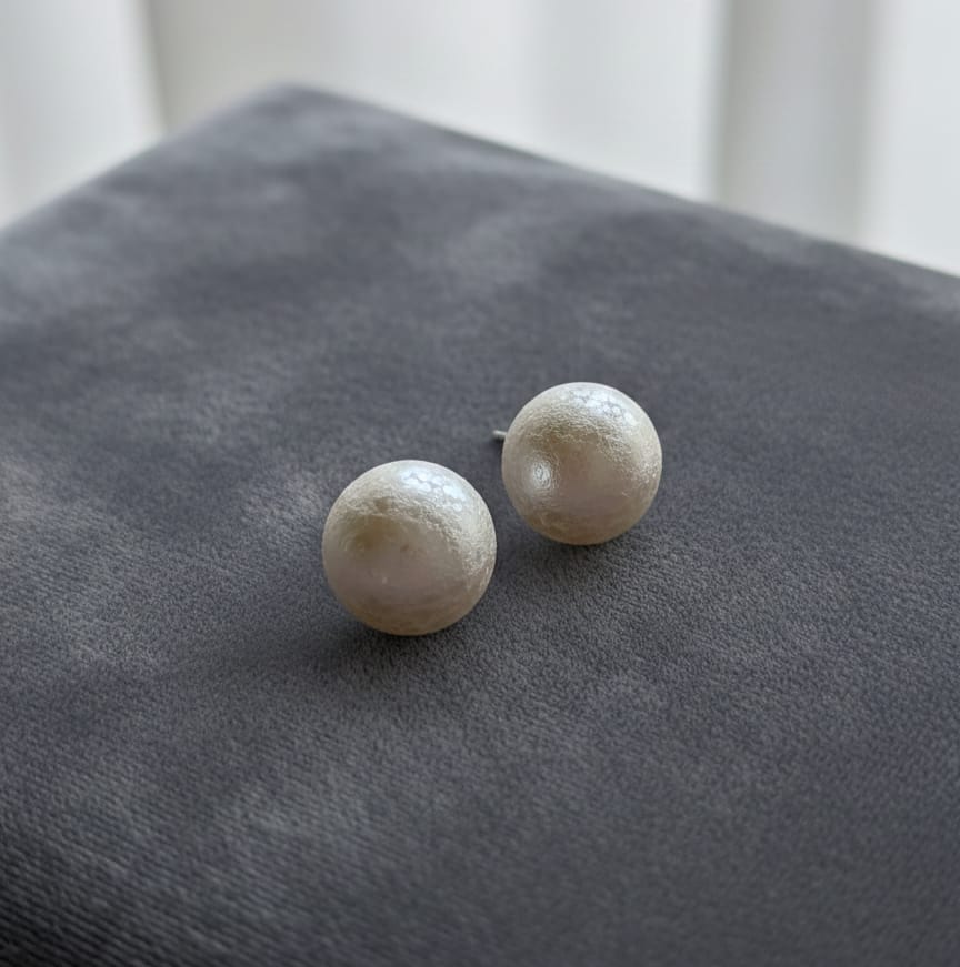 Pair of pearl stud earrings on a gray surface