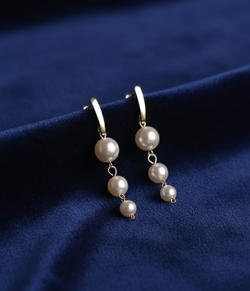 Pearl earrings on a blue fabric background