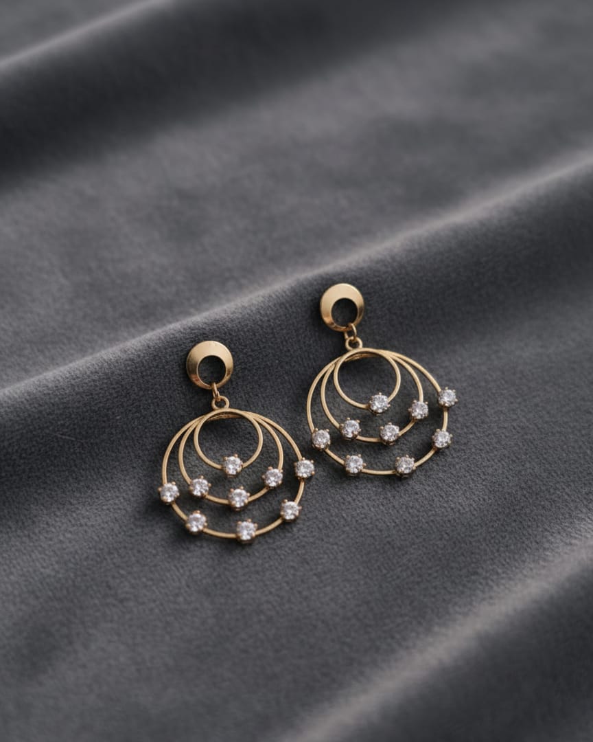 Gold hoop earrings with small diamonds on a gray fabric background