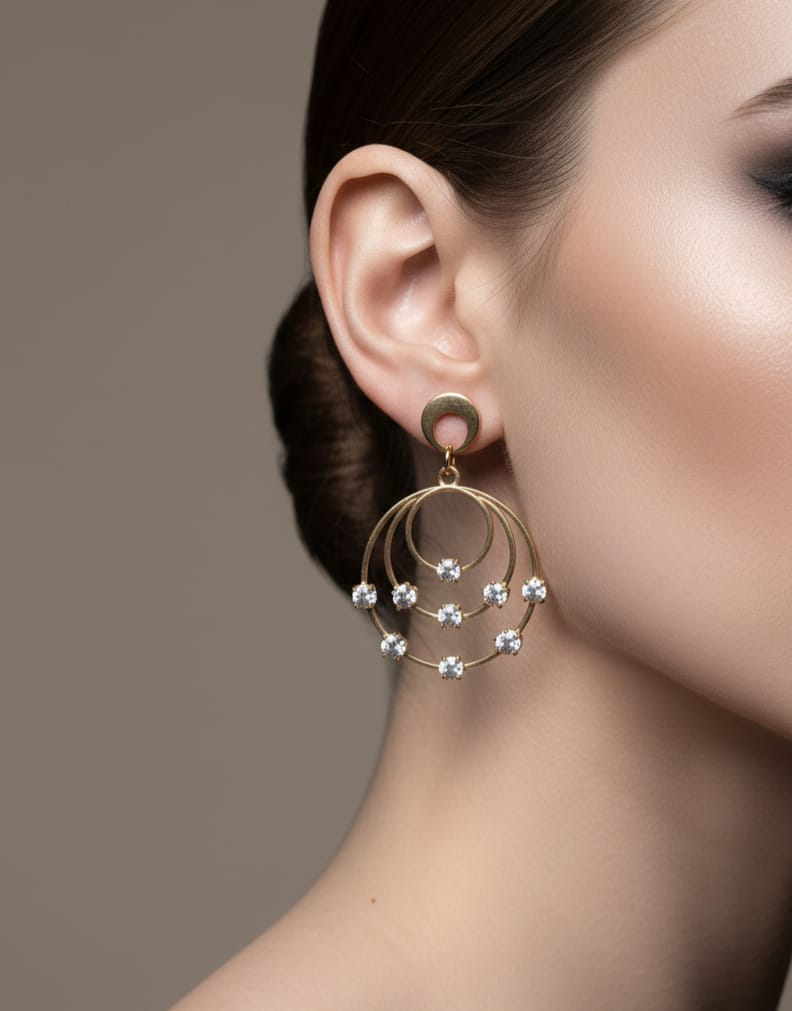 Close-up of a woman wearing a gold earring with small stones on a neutral background